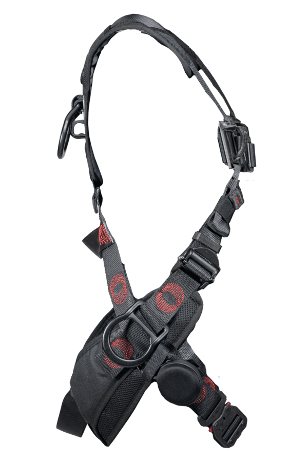 A detailed safety harness featuring adjustable straps, buckles, and padding for secure and comfortable wear. The harness is typically used for climbing or industrial work. It has adjustable black straps with red detailing to ensure a secure fit. The central buckle is prominent for easy fastening and unfastening. Grey padded areas provide comfort during wear, reducing pressure points. Multiple attachment points are visible for securing tools or connecting to safety lines. The design of the harness ensures weight distribution for the wearer’s safety and comfort.