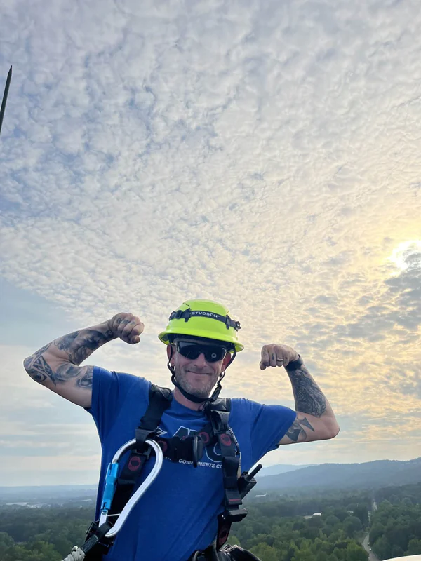 Dusty flexing on the tower at sunrise—suited up in his UnitySafe gear, living the tower life